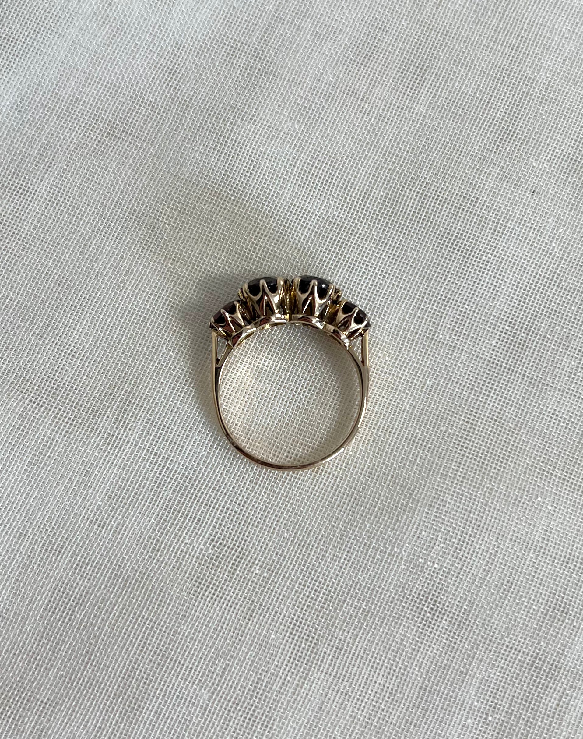 top view of gold red garnet set ring, on white fabric background