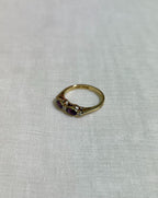 Gold ring with purple gemstones on a light beige fabric background