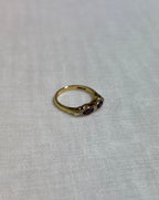 A gold ring with purple gemstones on cream fabric background