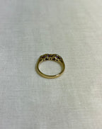 a gold ring with purple gemstones on light beige fabric background