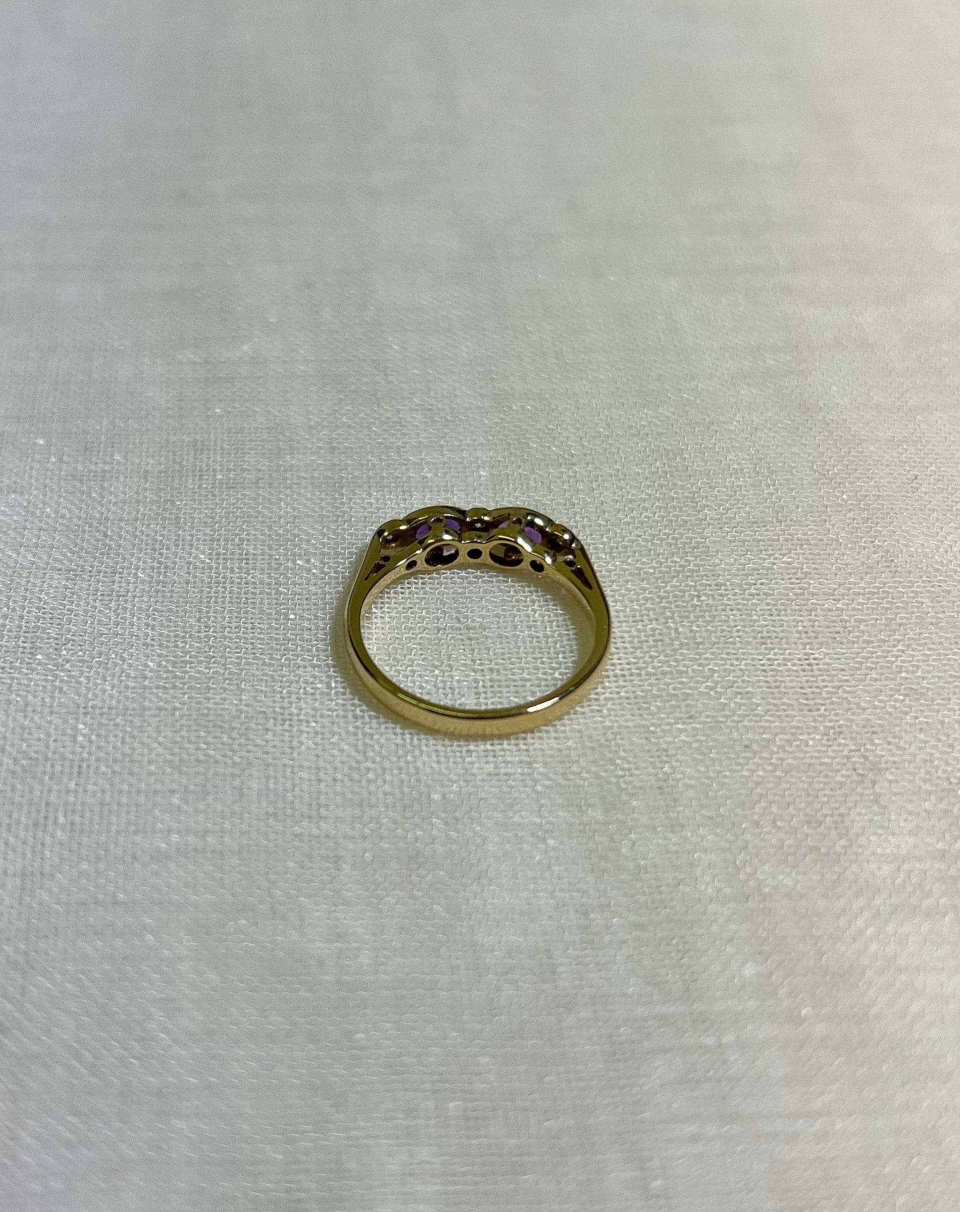 a gold ring with purple gemstones on light beige fabric background