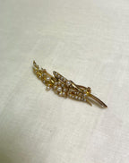 gold brooch with pearls on beige fabric background 