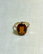 Gold Ring with oval citrine stone on white fabric background