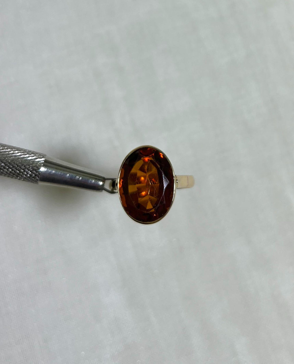 Gold Ring with orange stone on beige background