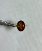 Gold Ring with orange stone on beige background