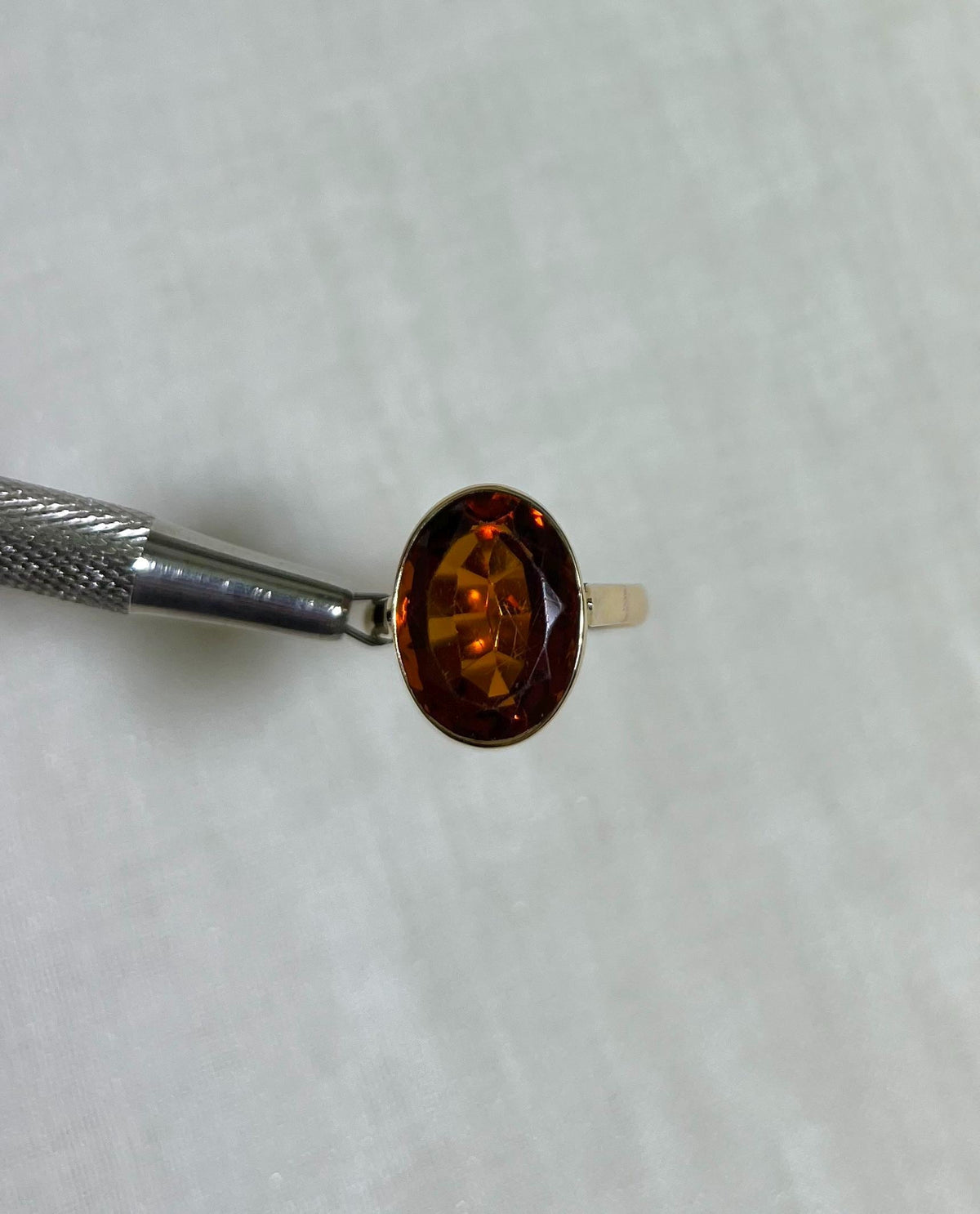 Gold Ring with orange stone on beige background