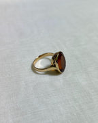 side view of Gold ring with orange stone on white fabric background