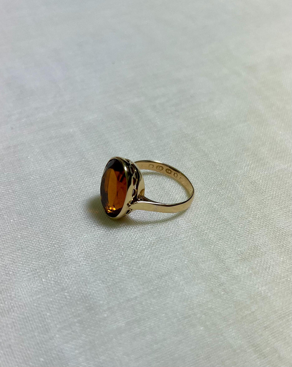 Gold ring with a amber coloured stone on a light fabric background