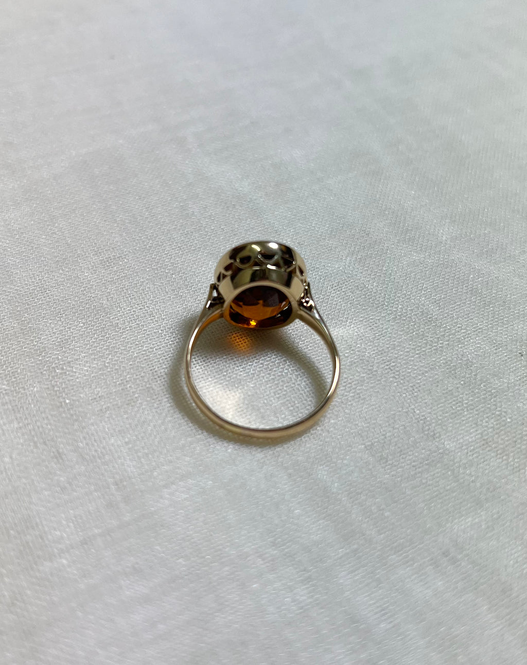 back view of gold ring on white fabric background