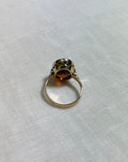 back view of gold ring on white fabric background