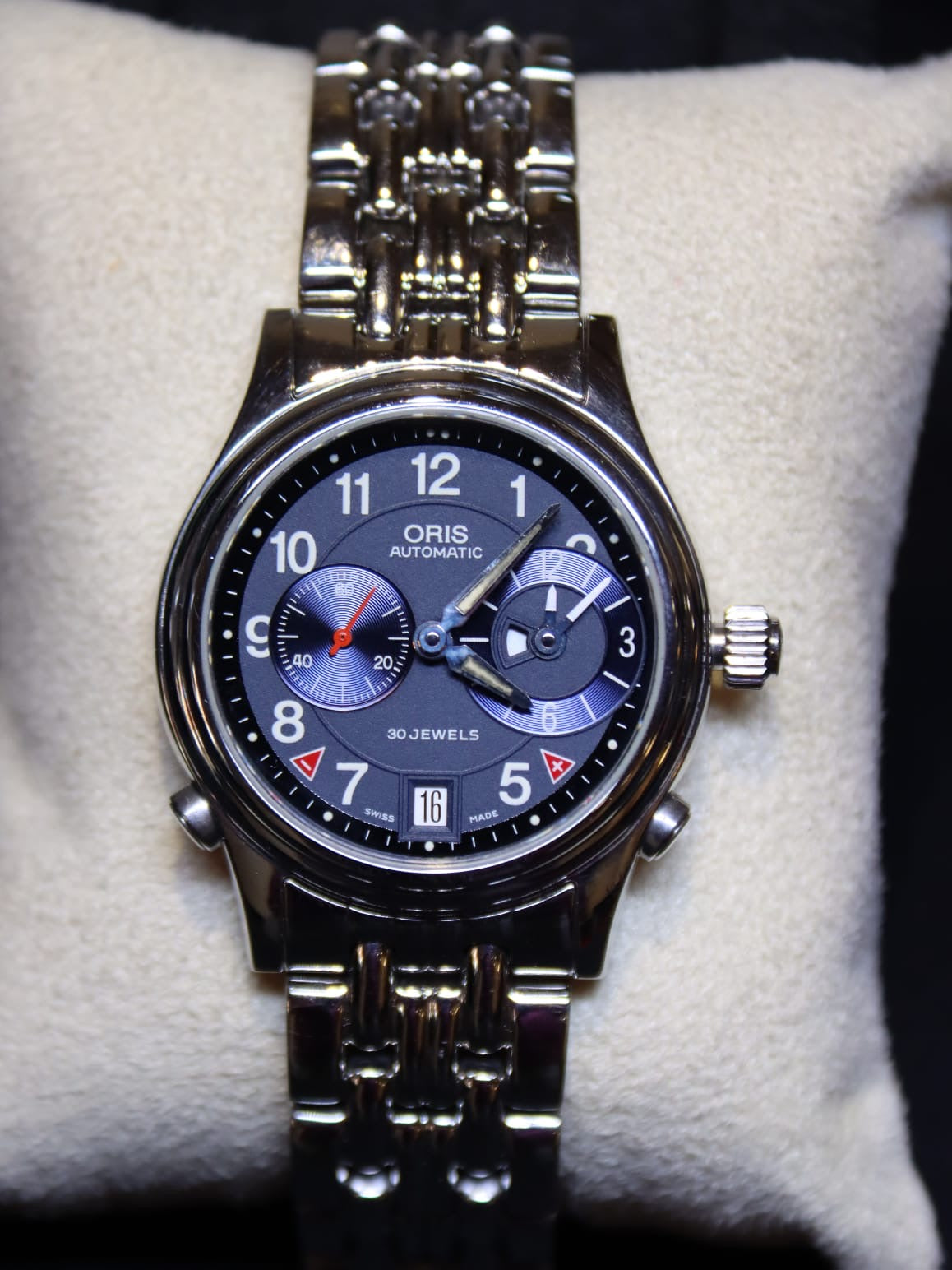 an Oris automatic watch with blue dial, resting on cream cushion