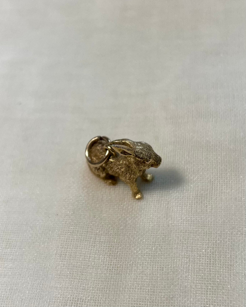 gold bunny charm on white fabric background 