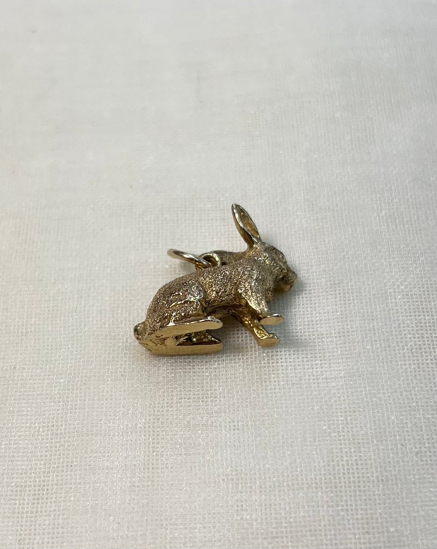 gold rabbit charm on white fabric background