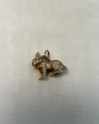 gold bunny rabbit charm on white fabric background 