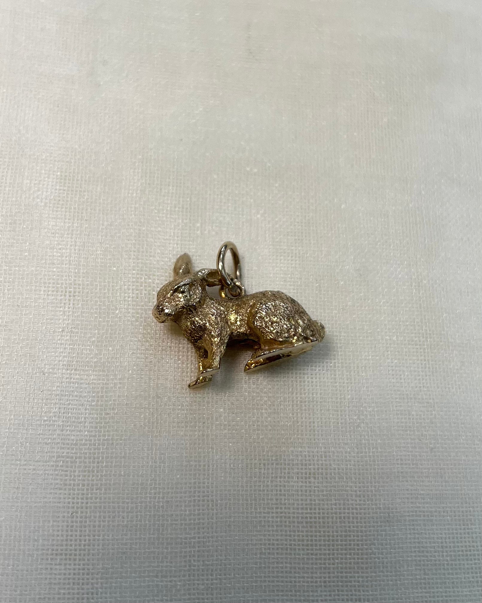 gold bunny rabbit charm on white fabric background 