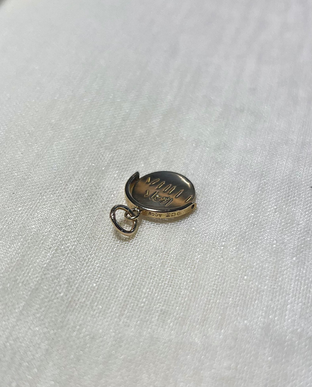 gold round charm with bale on cream fabric background