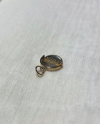 gold round charm with bale on cream fabric background