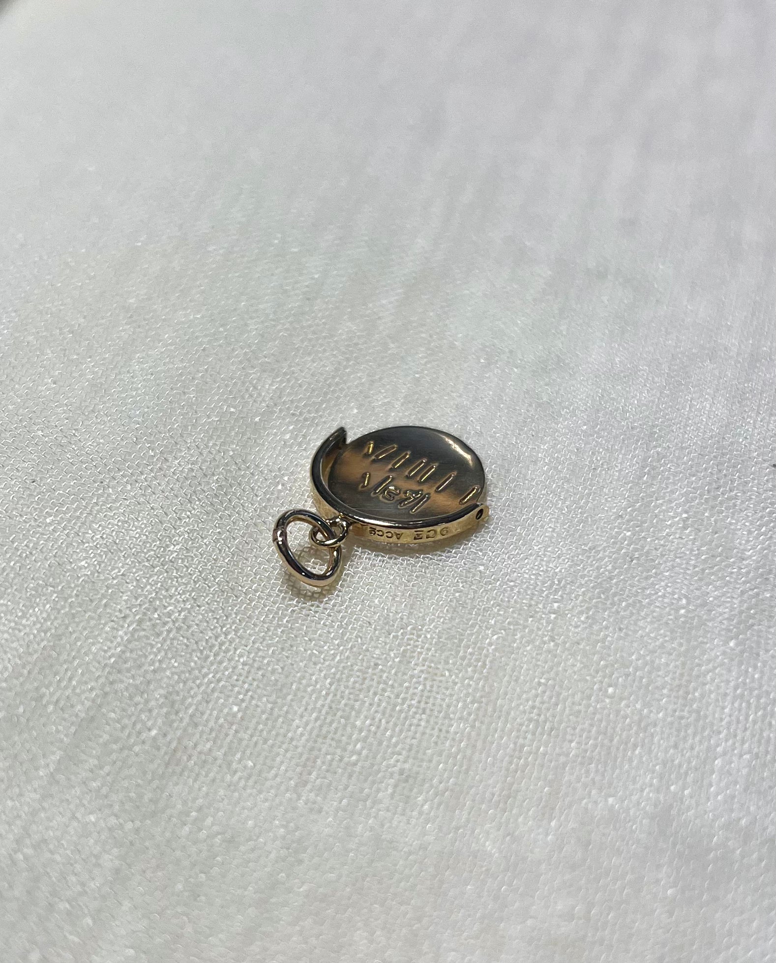 gold round charm with bale on cream fabric background