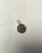 gold round charm with 'happy days' message on cream linen background 