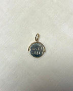 gold round charm with engraving on cream linen background