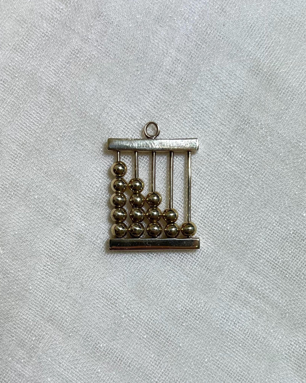 gold abacus charm on light beige background