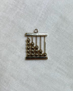 gold abacus charm on light beige background