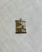 gold abacus charm on white fabric background 