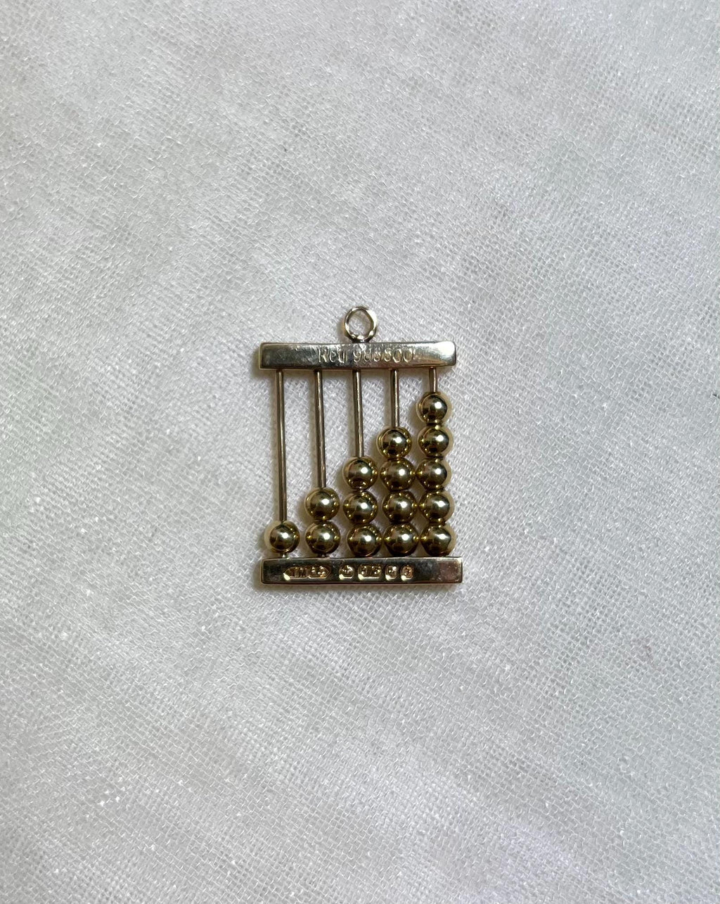 gold abacus charm on white fabric background