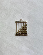 gold abacus charm on white fabric background