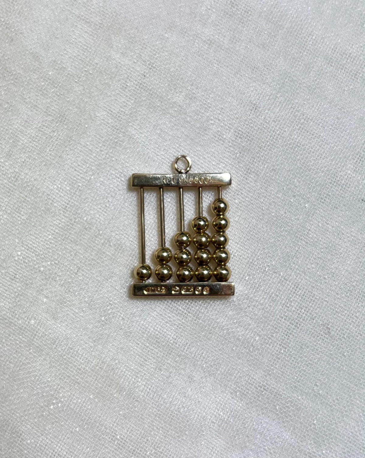 gold abacus charm on white fabric background