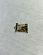 gold abacus charm on white fabric background