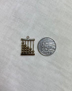 gold abacus charm next to ten pence coin for scale on white fabric background