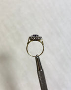 side view of gold ring held by silver tool above white background