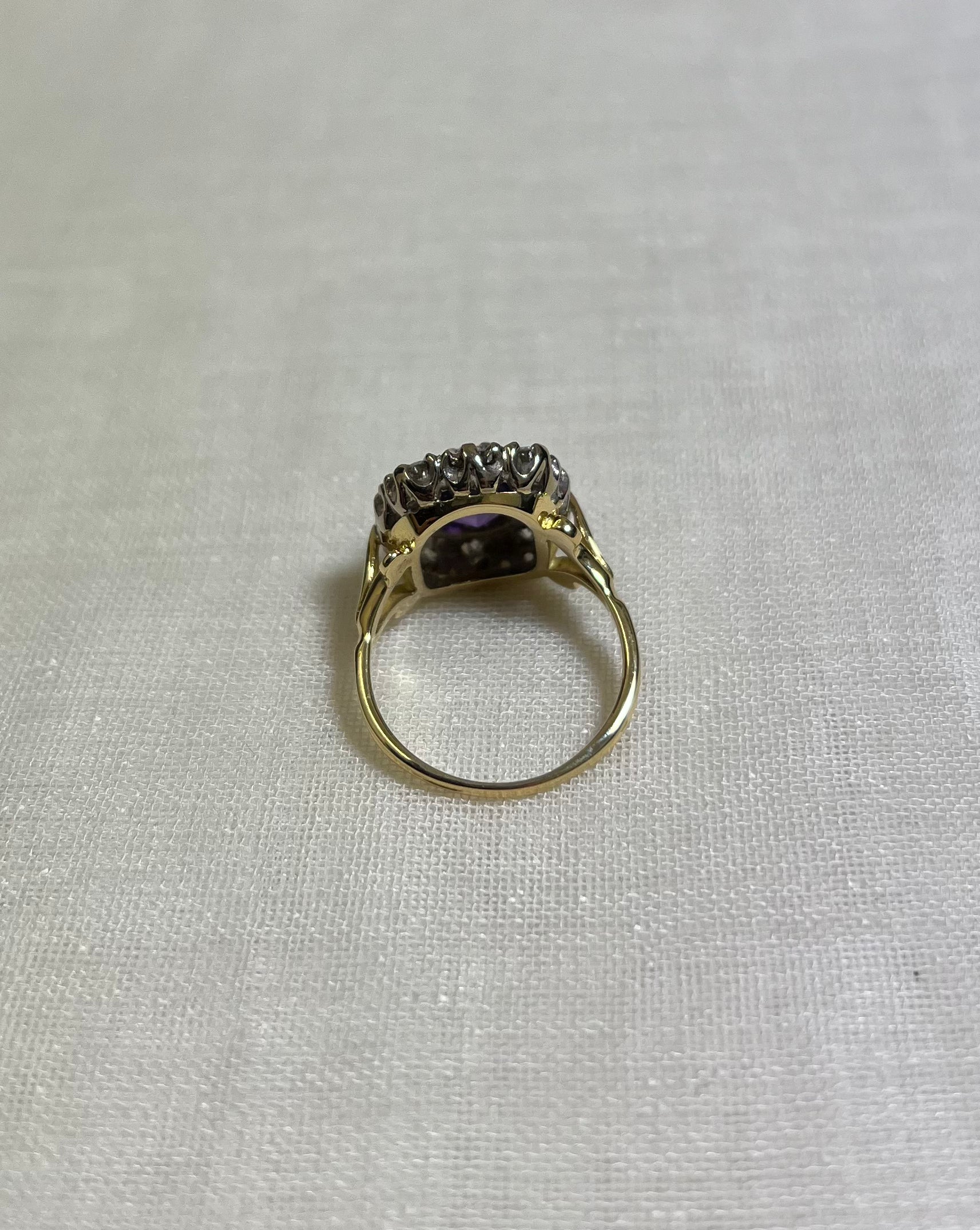 back view of gold ring resting on white fabric background
