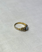 a gold ring with pearl and light blue cabochon, resting on cream linen background