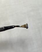 side view of gold ring head by silver tool above cream coloured background
