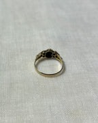 back view of gold stone set ring, resting on cream linen background