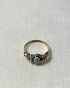 gold stone set ring with visible hallmark on the band, marked 375 with anchor symbol and letter G, resting on cream linen background