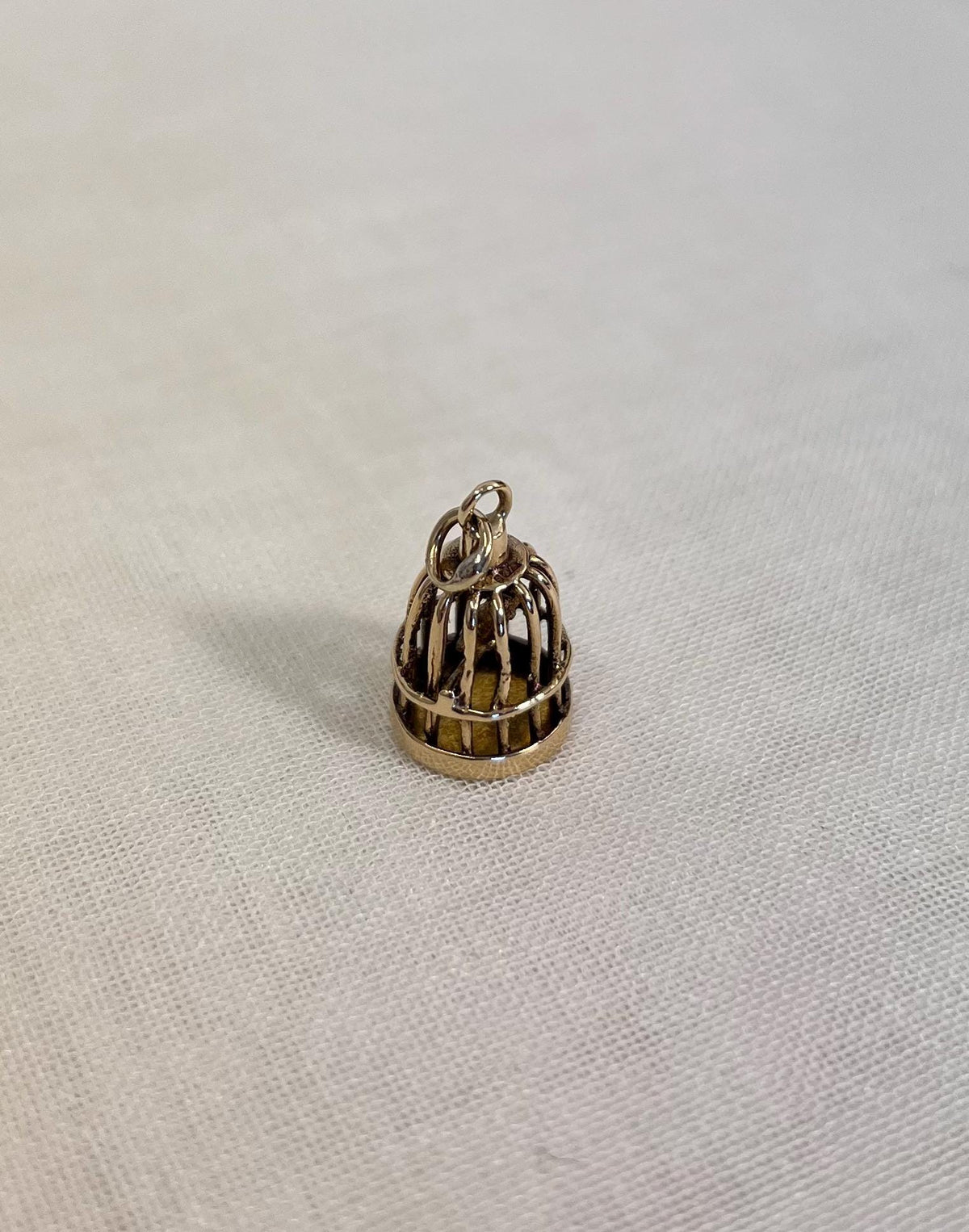 gold birdcage charm on fabric background