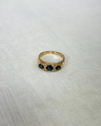 Gold ring with three blue stones on a light fabric background
