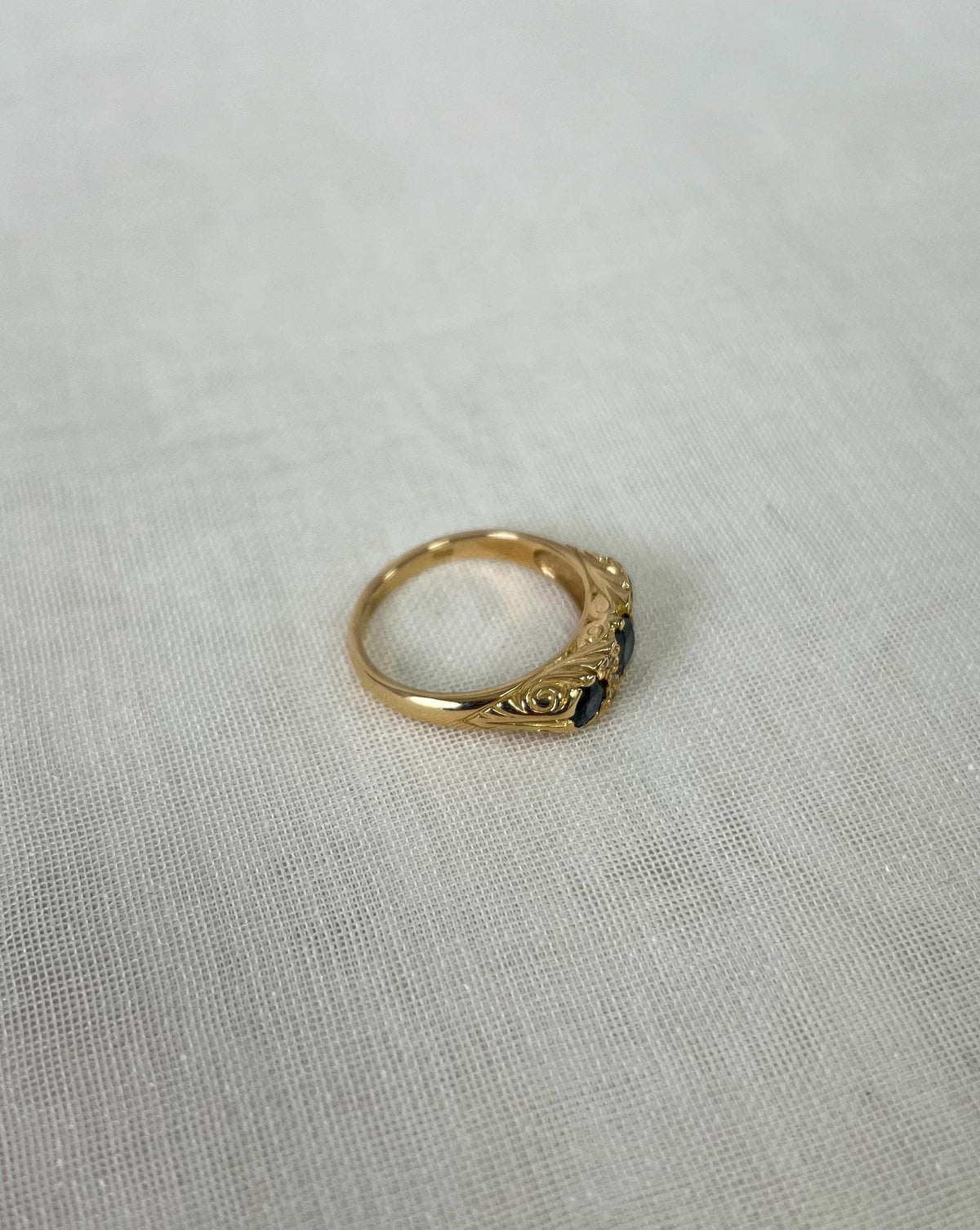 Gold ring with a blue gemstone on a light fabric background