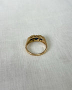Gold ring with three blue gemstones on a white fabric background
