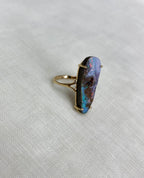 large opal ring side view, resting on white fabric background