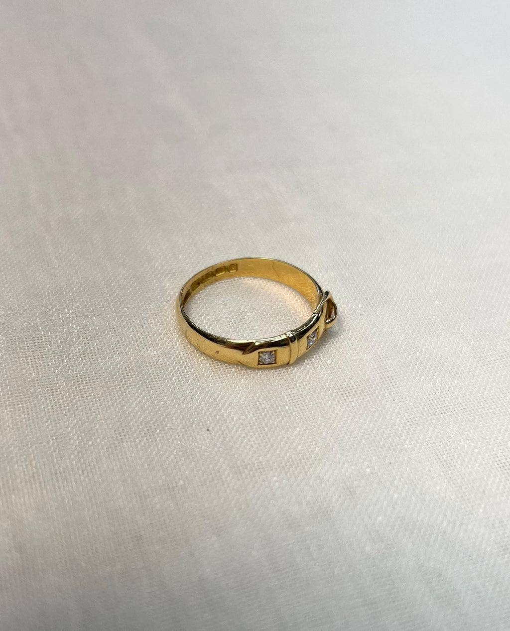 Gold ring with small diamonds on a light fabric background