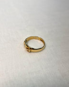 gold buckle ring resting on white fabric background