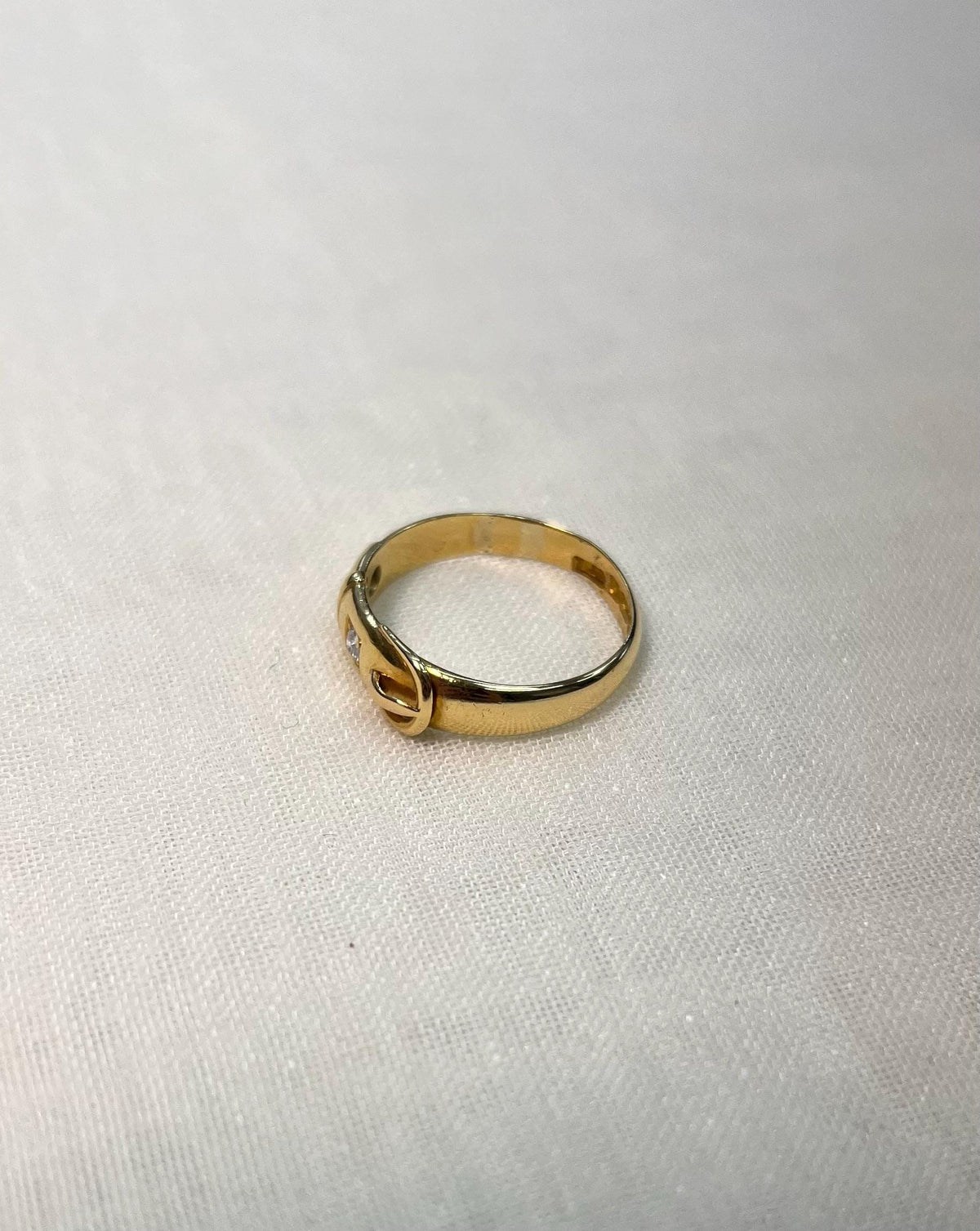 gold buckle ring resting on white fabric background