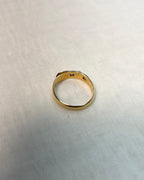 back view of gold band set with diamonds, resting on white fabric background 