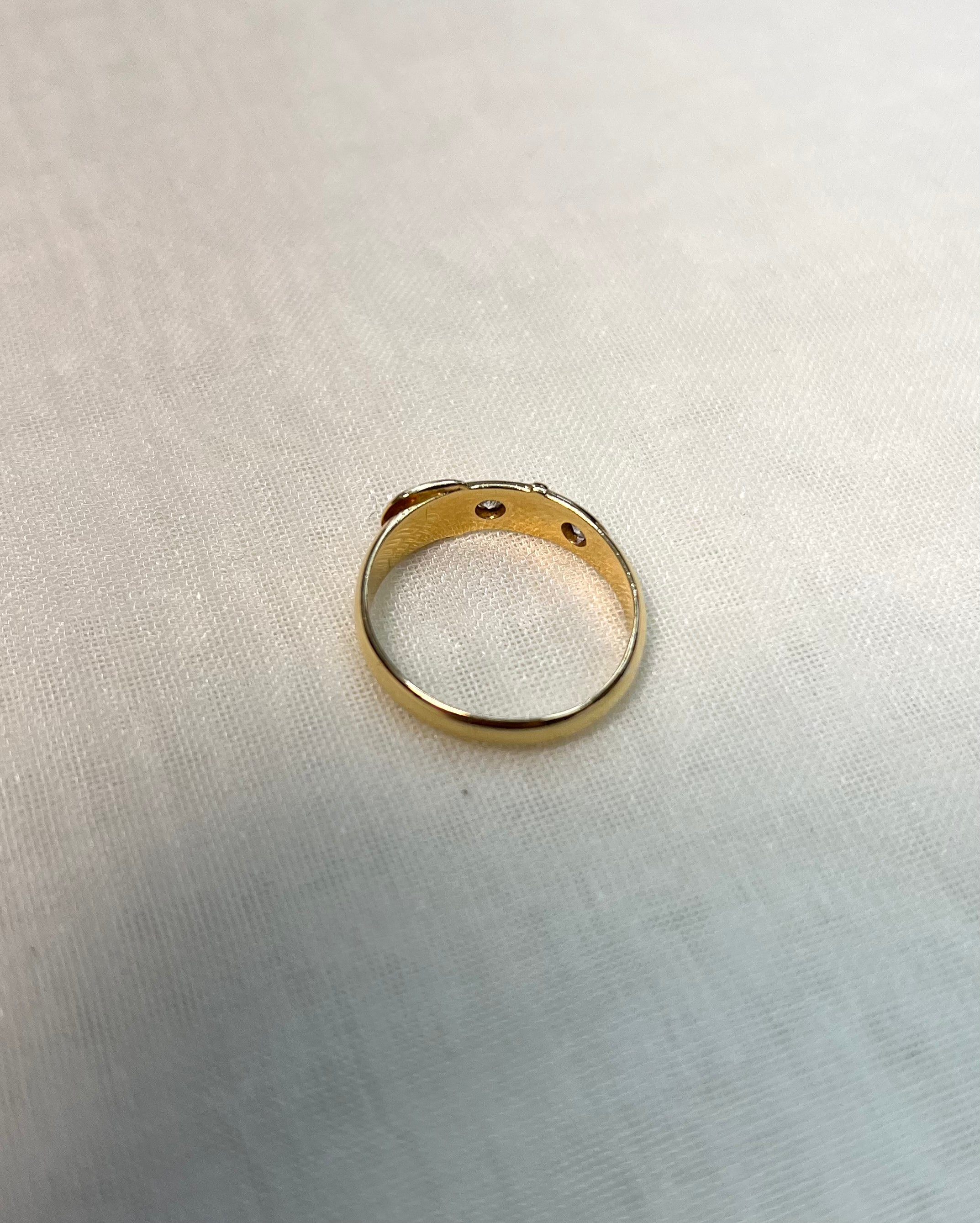 back view of gold band set with diamonds, resting on white fabric background 
