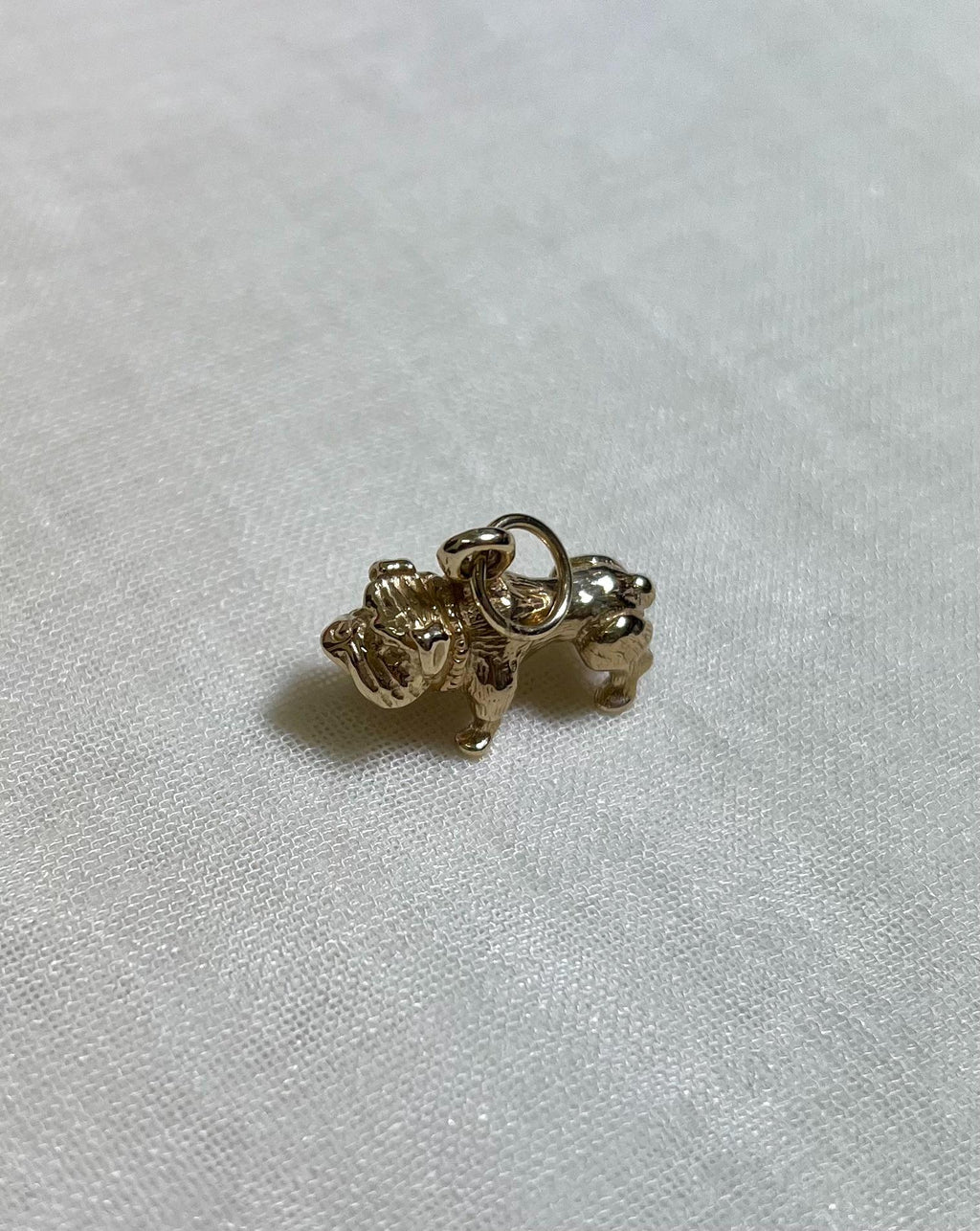 Gold dog-shaped charm on a white fabric background