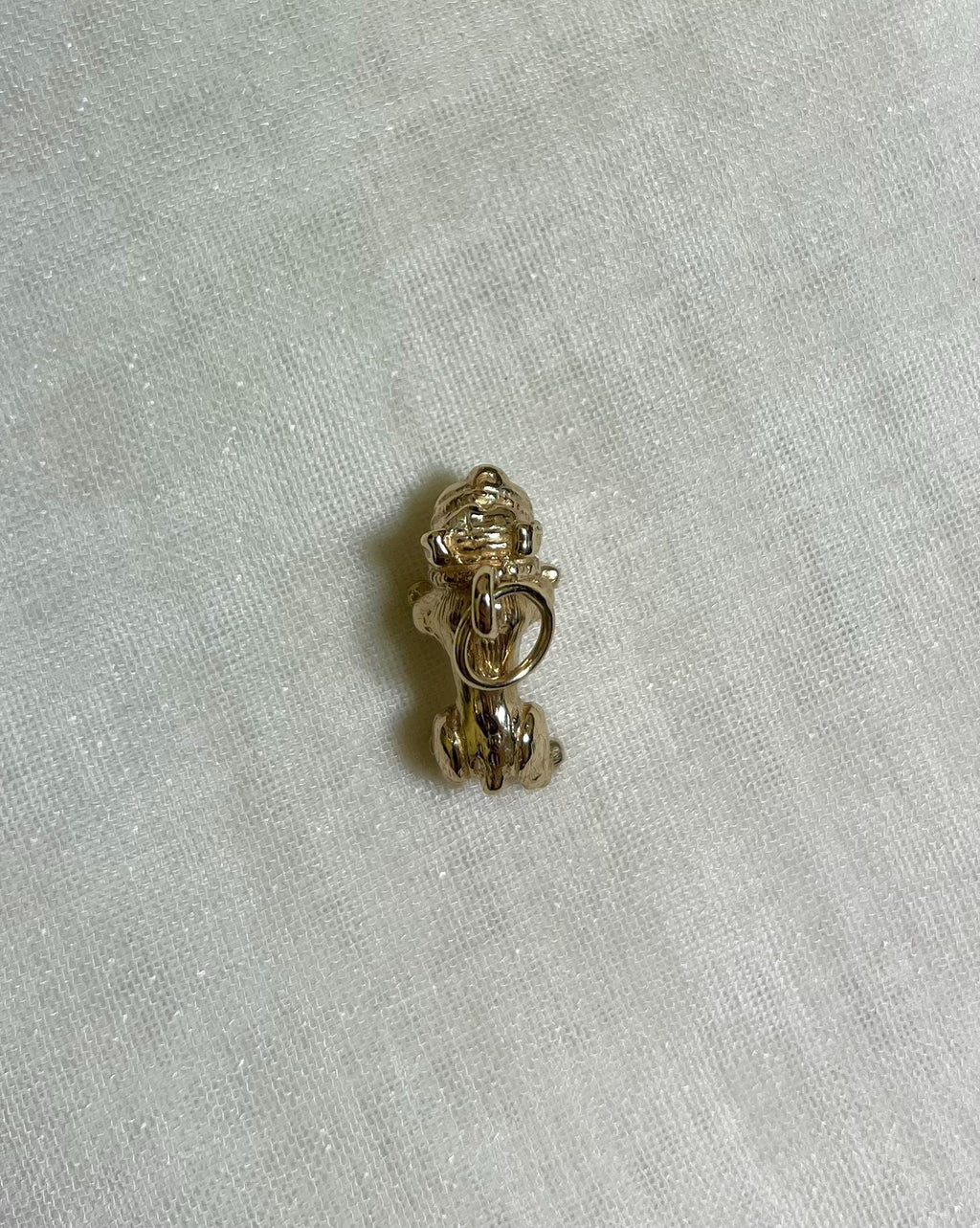 gold dog charm on light fabric background 
